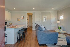 Modern living space featuring designer furnishings and a flat-screen SMART TV overlooking the fully equipped kitchen.