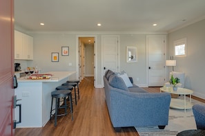 Modern living space featuring designer furnishings and a flat-screen SMART TV overlooking the fully equipped kitchen.