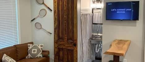 Character abounds throughout this space.  Notice the live edge bar height counter, as well as the antique sliding door.  In the rear of the photo is a shot of the bathroom with full sized shower, sink and toilet. 