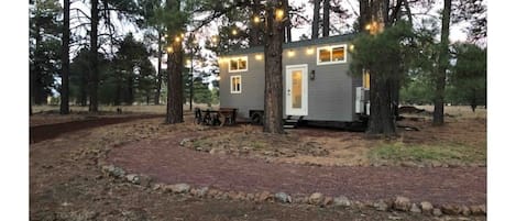 Exterior of the tiny house with dining table and chairs and bistro lighting 