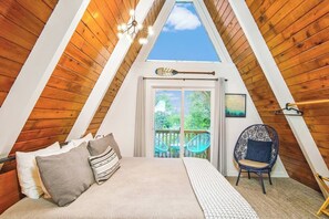 Relax in king bed luxury on a Casper mattress, nestled in crisp cotton sheets and a snug duvet. Embrace the treetops from the upper balcony featuring a quaint seating area and a glimpse of the ocean. Plan your adventures in this serene retreat!"