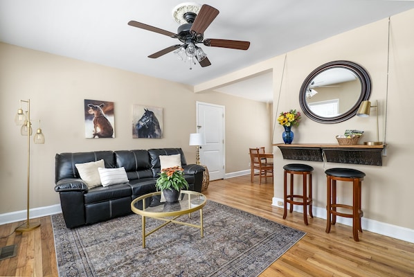 The living room is full of light and features a Roku TV and electric fireplace.
