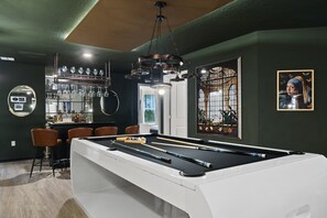 Stylish game room with pool table, bar, and artful decor for a relaxed stay.
