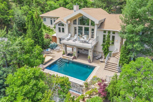 Aerial view of the entire home with the Infinity Pool, Hot Tub, Balcony and Patio Surrounded by Natural Landscaping