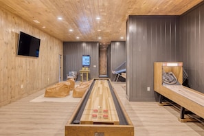 Game room with shuffleboard, TV, and arcade games