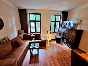 Wohnbereich mit Couch, TV und Esstisch
