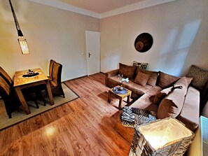 Wohnbereich mit Couch, TV und Esstisch
