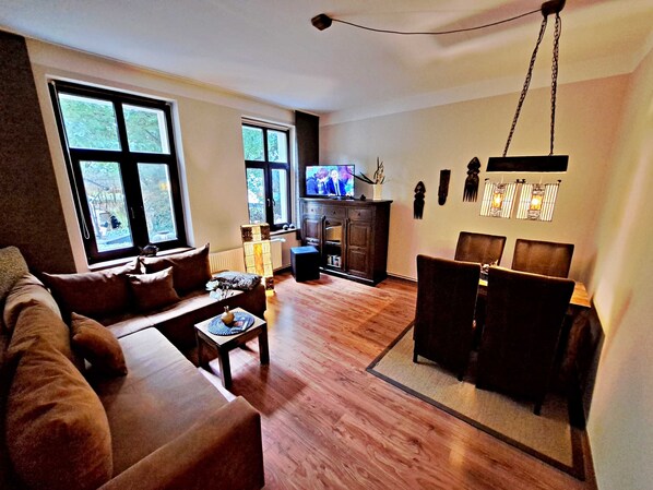Wohnbereich mit Couch, TV und Esstisch