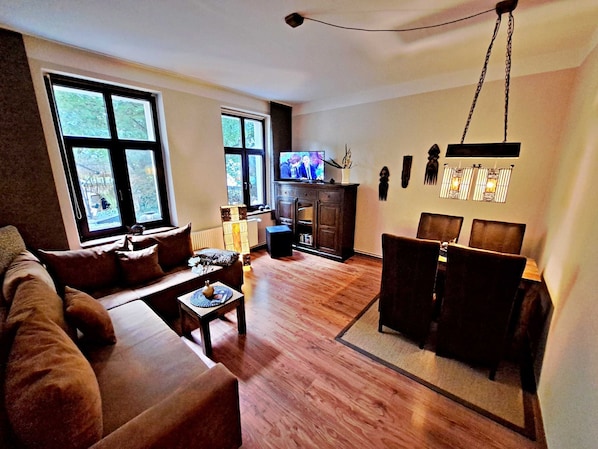 Wohnbereich mit Couch, TV und Esstisch