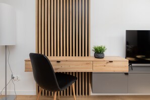 A workspace setup with a wooden desk, black chair, and decorative slatted wall, combining functionality and style.
