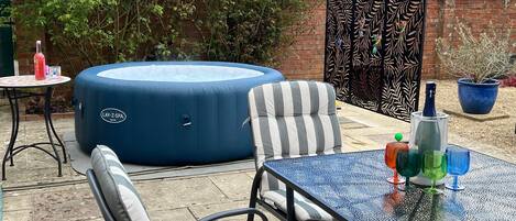 Spa pool and outside dining in walled courtyard garden
