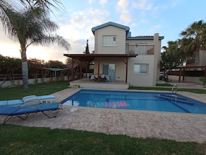 The villa. At left side barbeque area and at the right the covered garage.