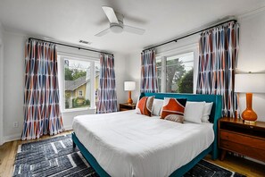 The bedroom boasts a king-size bed and is decorated with bright and welcoming colors, complemented by a modern smart TV, creating a cozy and inviting space perfect for a relaxing stay.