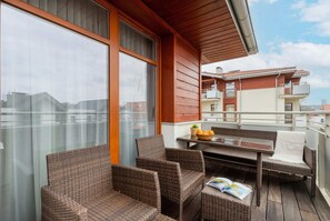 A spacious balcony with wicker furniture, offering a relaxing spot to enjoy outdoor views.