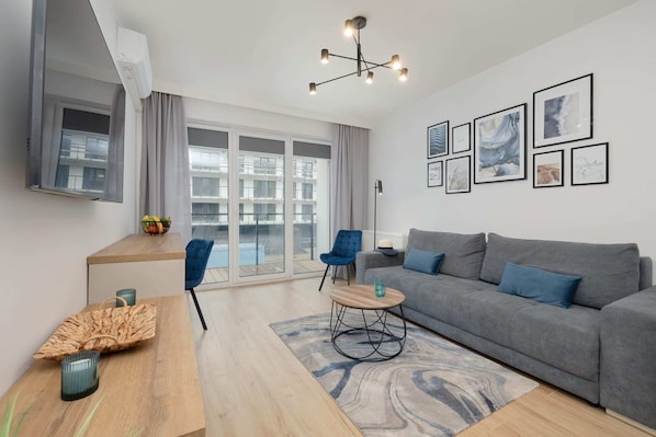 A modern living room with a grey sofa, a wooden coffee table, and framed artwork, creating a cozy and elegant atmosphere.