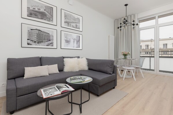 A cozy living room with a modern gray sofa, a glass coffee table, and stylish wall art.
