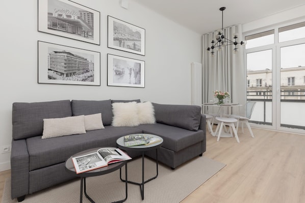 A cozy living room with a modern gray sofa, a glass coffee table, and stylish wall art.