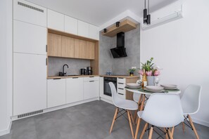 A compact kitchen and dining area featuring wooden cabinets, white countertops, and chic furniture.
