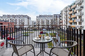 A balcony with a small table and chairs, overlooking a modern residential complex.
