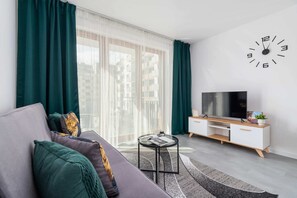 A living area with a grey sofa, vibrant cushions, and a stylish coffee table near a TV console.
