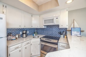 The recently updated kitchen features quartz countertops, tile backsplash and a stainless cooktop electric stove. 