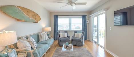 Step into this sunny coastal living room with surfboard art, light teal sofa, and natural textures, all illuminated by an abundance of natural light.