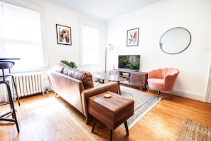 Spacious Living Room with Sofa, Smart TV, and Lounge Chair. 