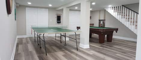 Game room with pool table, ping pong table and tv.