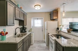 Large kitchen, countertop, double sink, glass stove, fridge, washer/dryer.