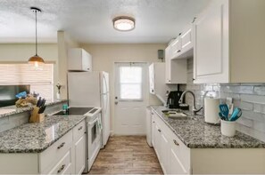 Large kitchen, countertop, glass stove, fridge, washer/dryer, double sink.