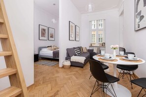 A combined dining and living area, with a wooden table, black chairs, and a gray sofa, creating an open and functional layout.