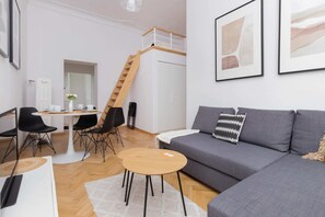 A cozy living room featuring a gray sofa, wooden coffee table, and modern wall art, illuminated by natural light from large windows.