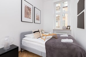 A bedroom with a neatly made double bed, gray throw blanket, and framed wall decor, offering a comfortable and stylish ambiance.