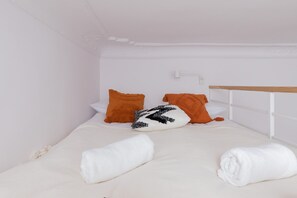 A minimalistic sleeping loft with a bed and bright orange cushions, ideal for a cozy rest space.