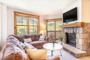 Living are with large sectional couch, flatscreen TV, gas fireplace and private balcony.