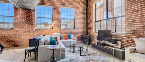 Living Room with Beautiful Exposed Brick Walls, Fireplace, Tin and Vaulted Ceilings, and Smart TV