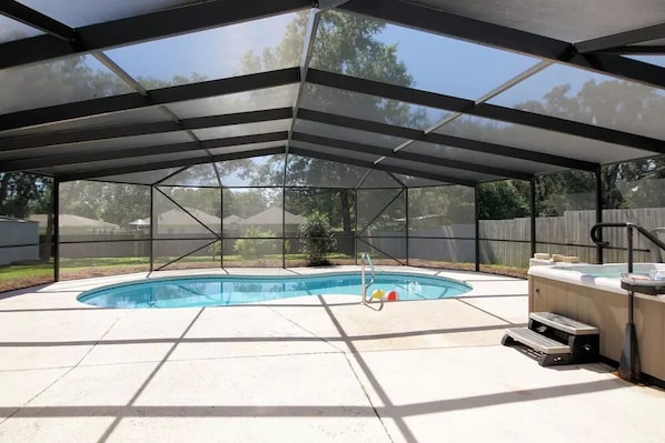 The pool, hot tub, and the back patio area are all in a screened enclosure