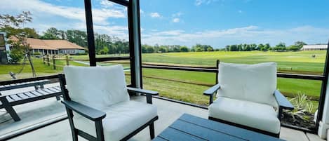 Screened patio seating overlooking the driving range at Barefoot Resort. 