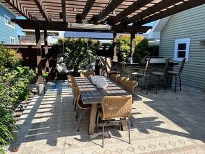 Gorgeous private backyard with new outdoor farmhouse table that seats 8-10, two comfy hanging egg chairs, and bar seating for six around an outdoor kitchen with grill and sink