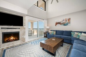 Spacious living room featuring sectional, marble fireplace, smart TV, and stunning ocean views