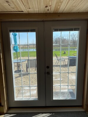 View of the stone patio and the pond through the french doors