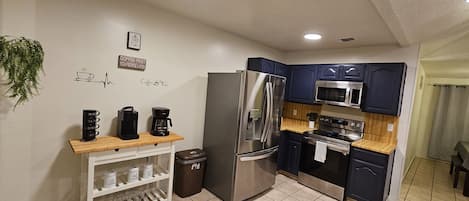 Kitchen with coffee bar, stainless steel fridge, stove, microwave and dishwasher