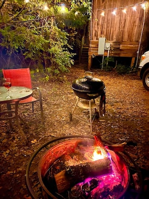 Firepit area with string lights, seating and a charcoal grill for a perfect romantic Winter night!