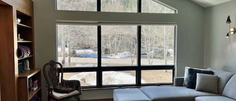 Living room has high ceilings, white oak flooring, and looks out the front yard.