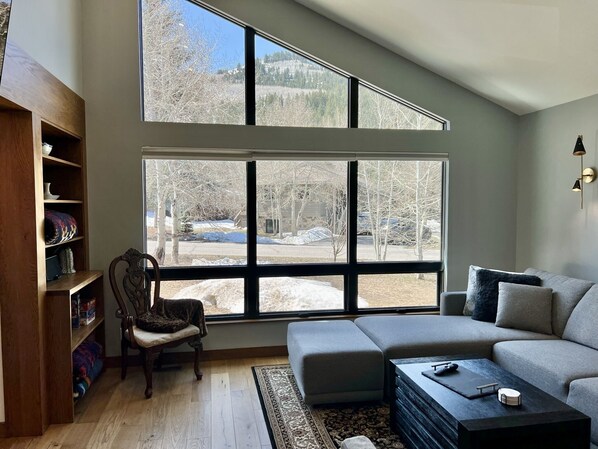 Living room has high ceilings, white oak flooring, and looks out the front yard.