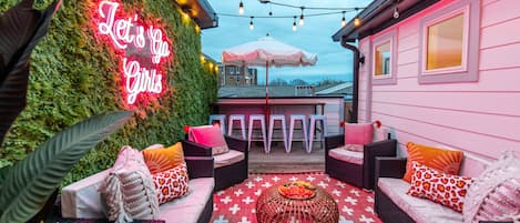 Top-floor rooftop patio lounge with downtown skyline views, Instagrammable murals, and neon lights. Relax in any of the comfortable chairs/sofas, or dine at the overlooking bar! To make it more memorable, it is also draped in bistro lights to make every night a starry one.