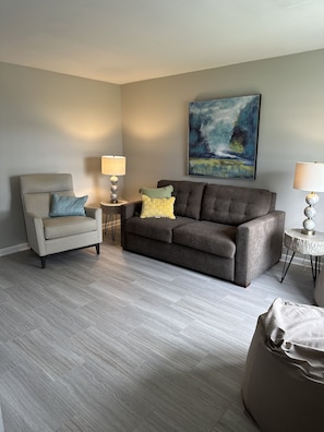 Living room with TV, pull out couch, a lounge chair and bean bags.