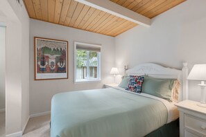 Across from the bathroom on the ground floor is a bedroom with a Queen bed and a dresser just out of frame on the left