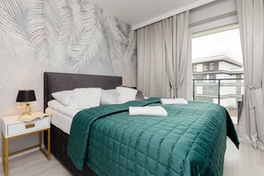 A cozy bedroom featuring a large bed with emerald green bedding and modern decor.
