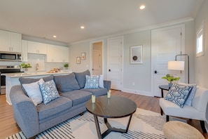 Unit 1: Modern Living Space featuring designer furnishings and a flat-screen SMART TV overlooking the fully equipped kitchen.